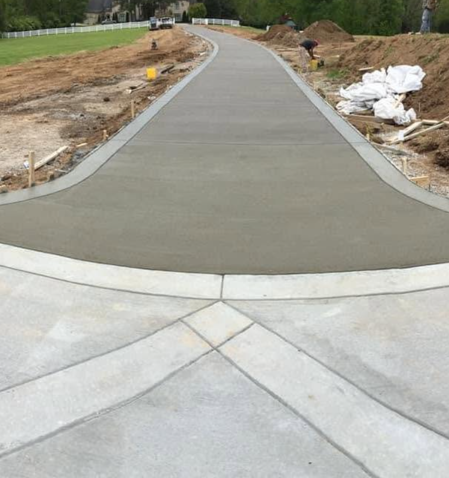 Exposed aggregate concrete walkway joining a stamped driveway apron